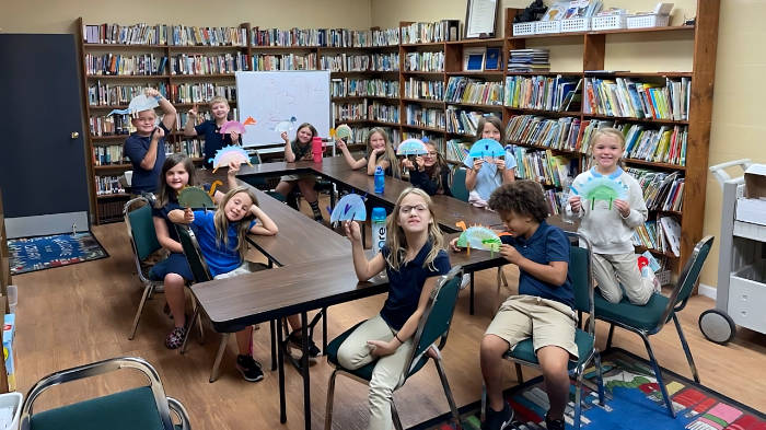 Elementary grade children showing off an art project in Christian school library