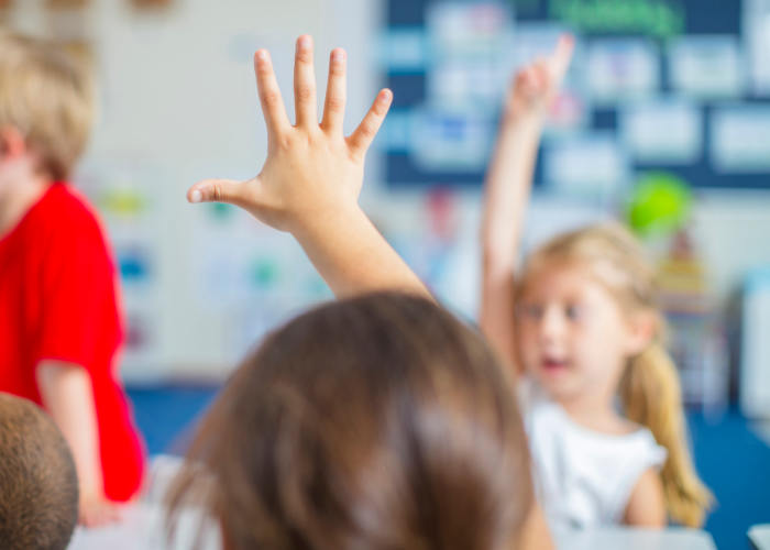 Preschool children raising their hands to answer a question