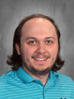 Cameron Akers smiling in a blue striped shirt