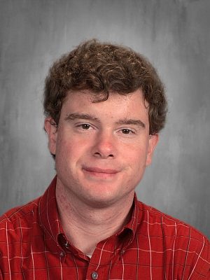 Connor Crace in a red checkered shirt against a gray background.