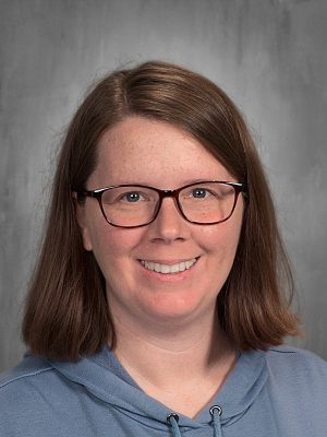 Headshot of Susan Trimble, smiling woman with glasses and a blue hoodie.